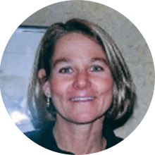 A smiling expert with shoulder-length blond hair, wearing a dark top, in a circular cropped photo with a beige background.