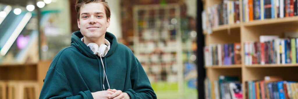 A male student in a wheelchair smiling in the library.