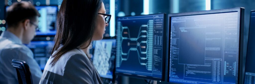 Man and woman sitting in front of bank of computer screens.