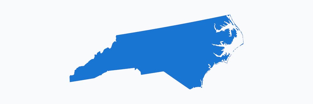 A simple, solid blue silhouette map of the state of North Carolina against a white background.